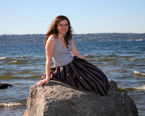 Senior girl sitting on rock in Lake Washington at Luther Burbank Park on Mercer Island