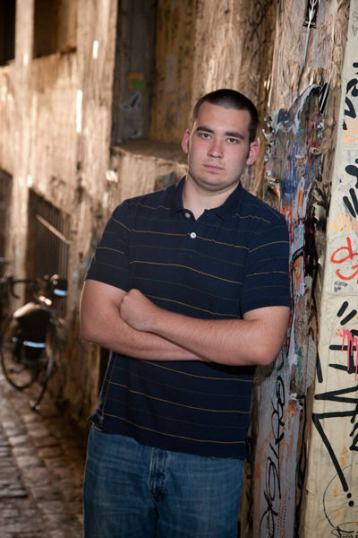 Senior boy leaning against wall in alley in Pike Place Market in Seattle