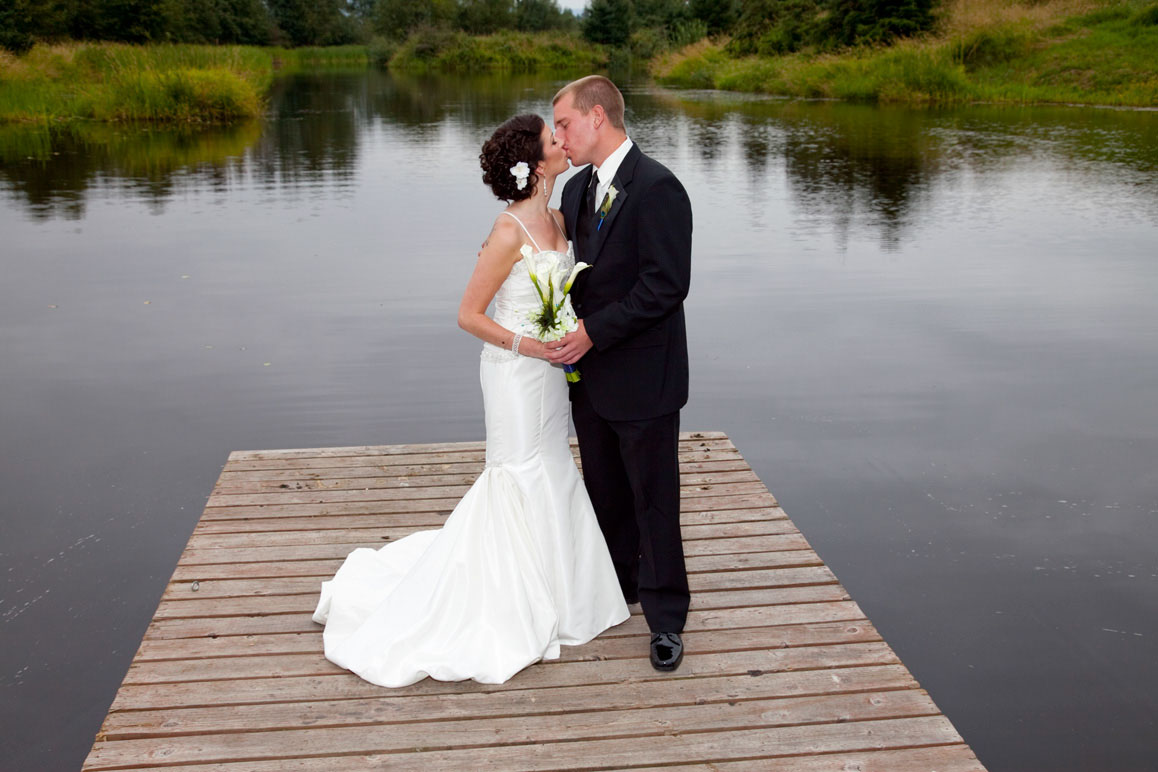 Bride and groom standing on dock and kissing at Lord Hill Farm in Monroe